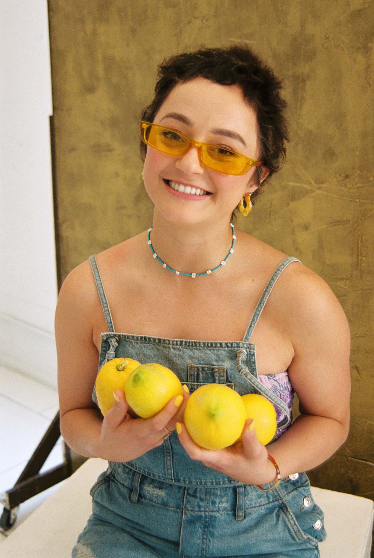 Kasey holding lemons in yellow sunglasses